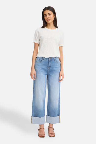 Wijde spijkerbroek in middinblauw denim van Fransa, met omslag en gedragen met een wit T-shirt en bruine sandalen.