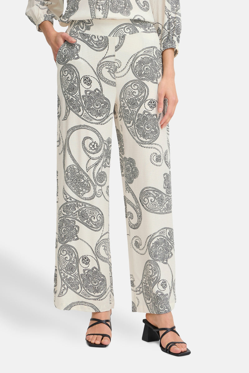 Ecru broek met paisleyprint van Fransa, losse pasvorm en wijde pijpen, gedragen met zwarte hakken.