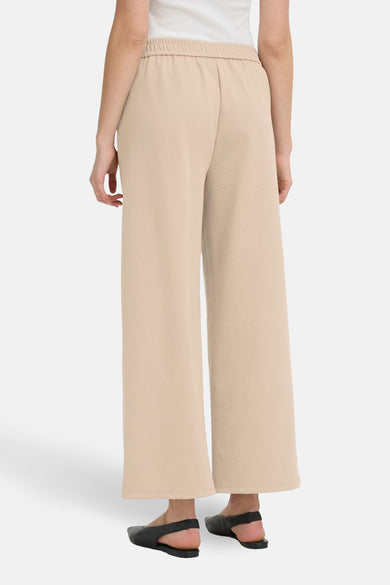 Beige kostuumbroek van Fransa, losse pasvorm en elastische taille, gedragen met een witte tanktop.