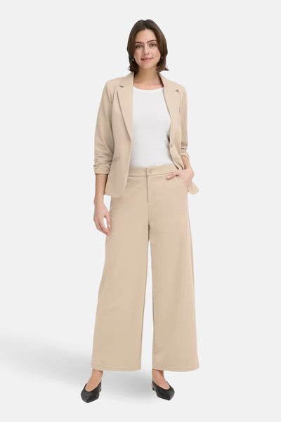 Pantalon de costume beige de Fransa, coupe ample et jambes larges, porté avec un blazer coordonné et un t-shirt blanc.