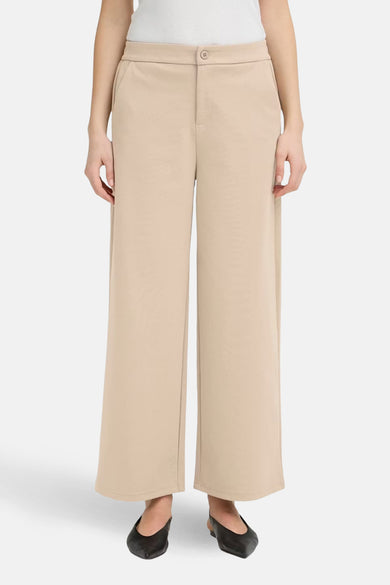 Beige kostuumbroek uit Frankrijk, met een wijde pasvorm en zijzakken, gedragen met zwarte ballerina's.