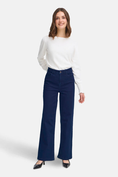 Jean large bleu foncé de Fransa, porté avec un pull blanc à manches longues et des escarpins noirs.