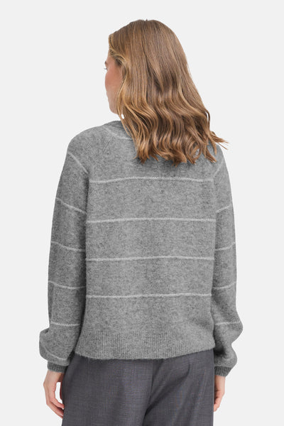 Cardigan gris chiné de Fransa, à rayures horizontales blanches, porté avec un pantalon gris.
