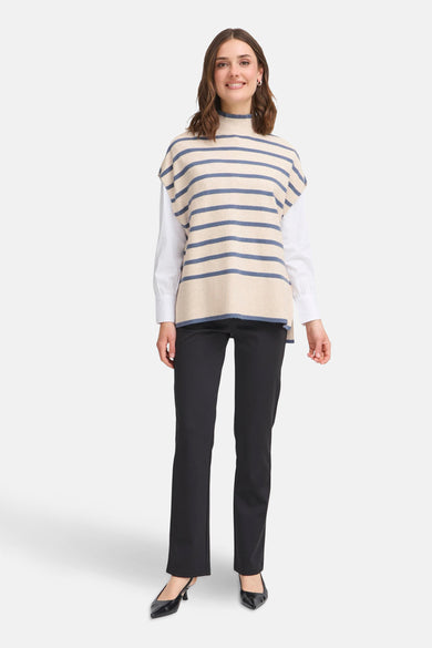 Débardeur tricoté multicolore par Fransa, à rayures bleues, porté sur une chemise blanche avec un pantalon noir.