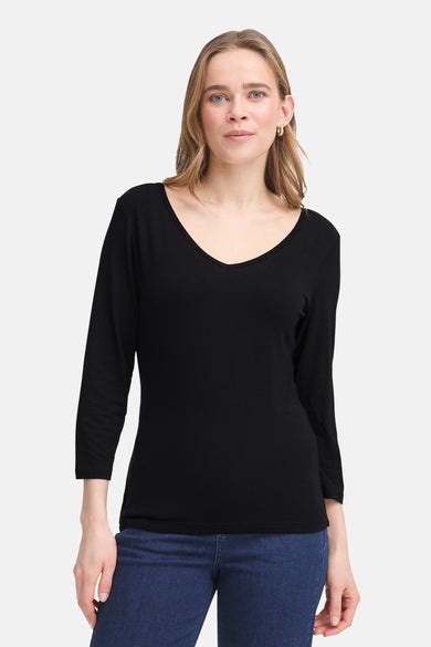 T-shirt noir à manches longues de Fransa, porté avec un jean bleu, et des boucles d'oreilles dorées.