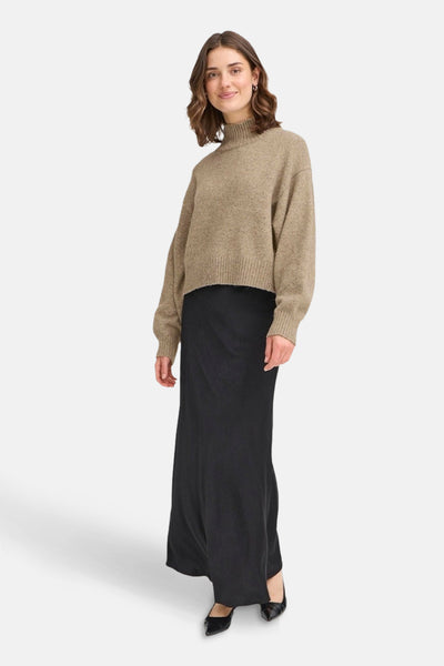 Beige coltrui van Fransa, gedragen met een lange zwarte rok en zwarte puntige schoenen.