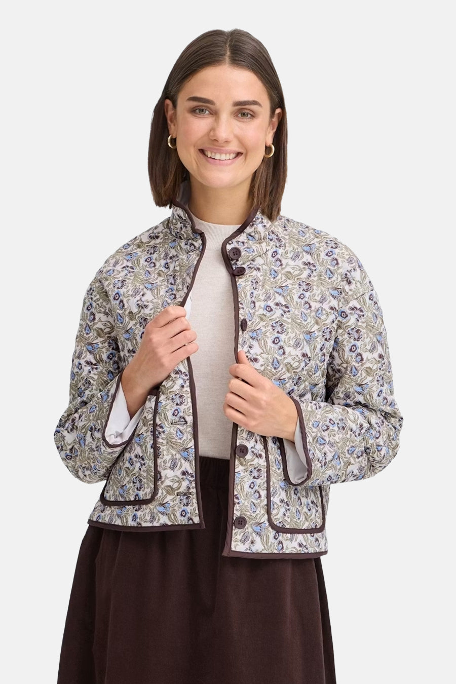 Multicolored floral-patterned women's casual jacket with brown trim and front buttons, worn over a beige top and dark skirt, front view