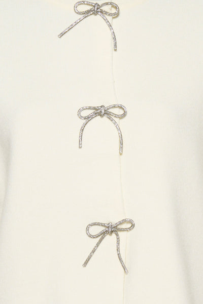 Cardigan écru de Fransa avec trois nœuds décoratifs scintillants le long de la patte de boutonnage.
