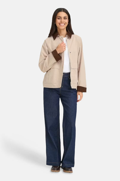 Veste courte beige par Fransa, avec col et poignets marron foncé, portée avec un t-shirt blanc et un jean bleu foncé.