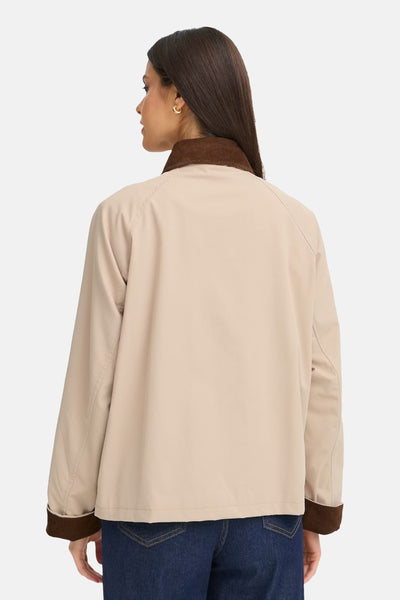 Veste courte beige de Fransa, avec un col marron en velours côtelé, portée avec un jean bleu foncé.