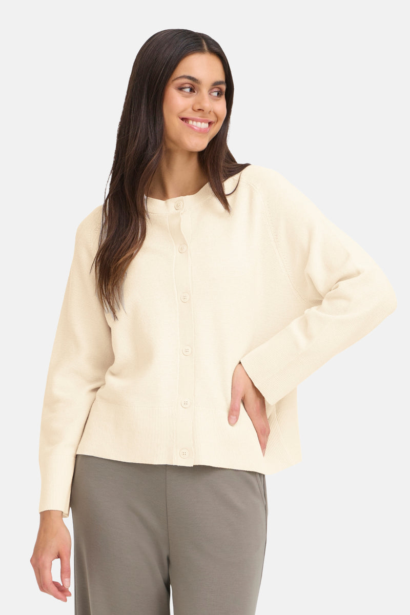 Cardigan beige de Fransa, avec une texture tricotée fine et une coupe décontractée sur un pantalon taupe.
