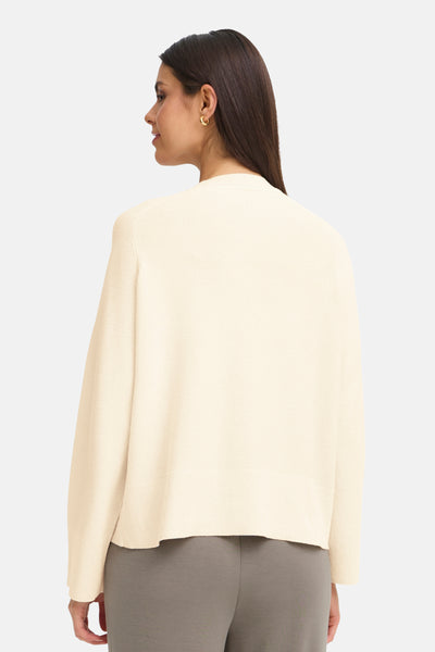 Cardigan beige, en maille texturée par Fransa, porté avec un pantalon gris uni.