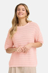 Pull rose à col rond de Fransa, en maille ajourée à rayures horizontales, porté avec un pantalon beige.
