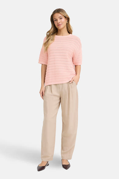 Pull à col rond rose de Fransa, à mailles ajourées horizontales, porté avec un pantalon beige ample.

