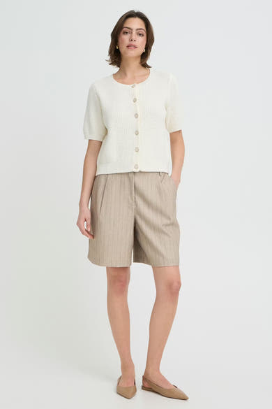 Short brun de Fransa, à rayures fines, porté avec un cardigan blanc et des ballerines beiges.