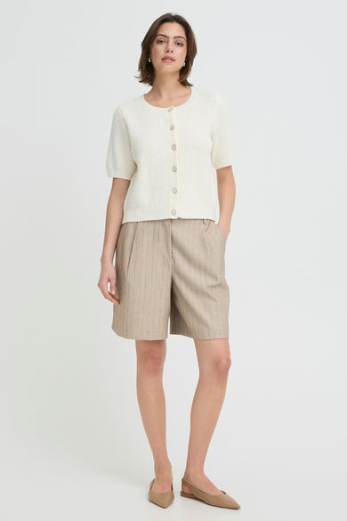 Short brun de Fransa, à rayures fines, porté avec un cardigan blanc et des ballerines beiges.