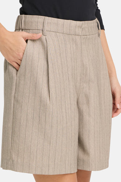 Short brun de Fransa, avec motif à rayures fines et plis structurés, porté avec un haut noir.