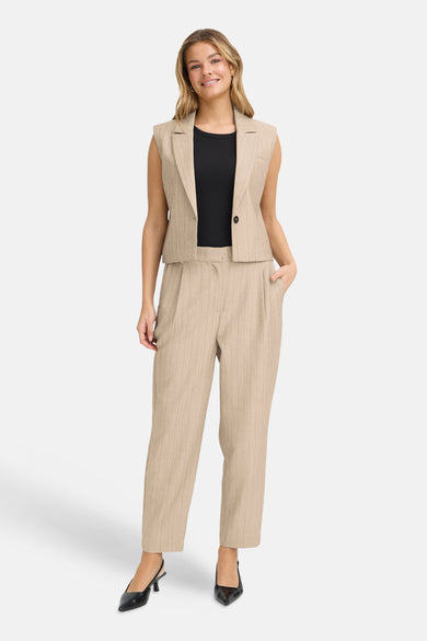 Beige blazer uit Frankrijk, gedragen met een zwart T-shirt en een bijpassende gestreepte broek, zwarte hakken.