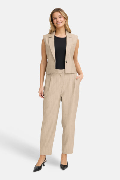 Beige blazer uit Frankrijk, gedragen met een zwart T-shirt en een bijpassende gestreepte broek, zwarte hakken.