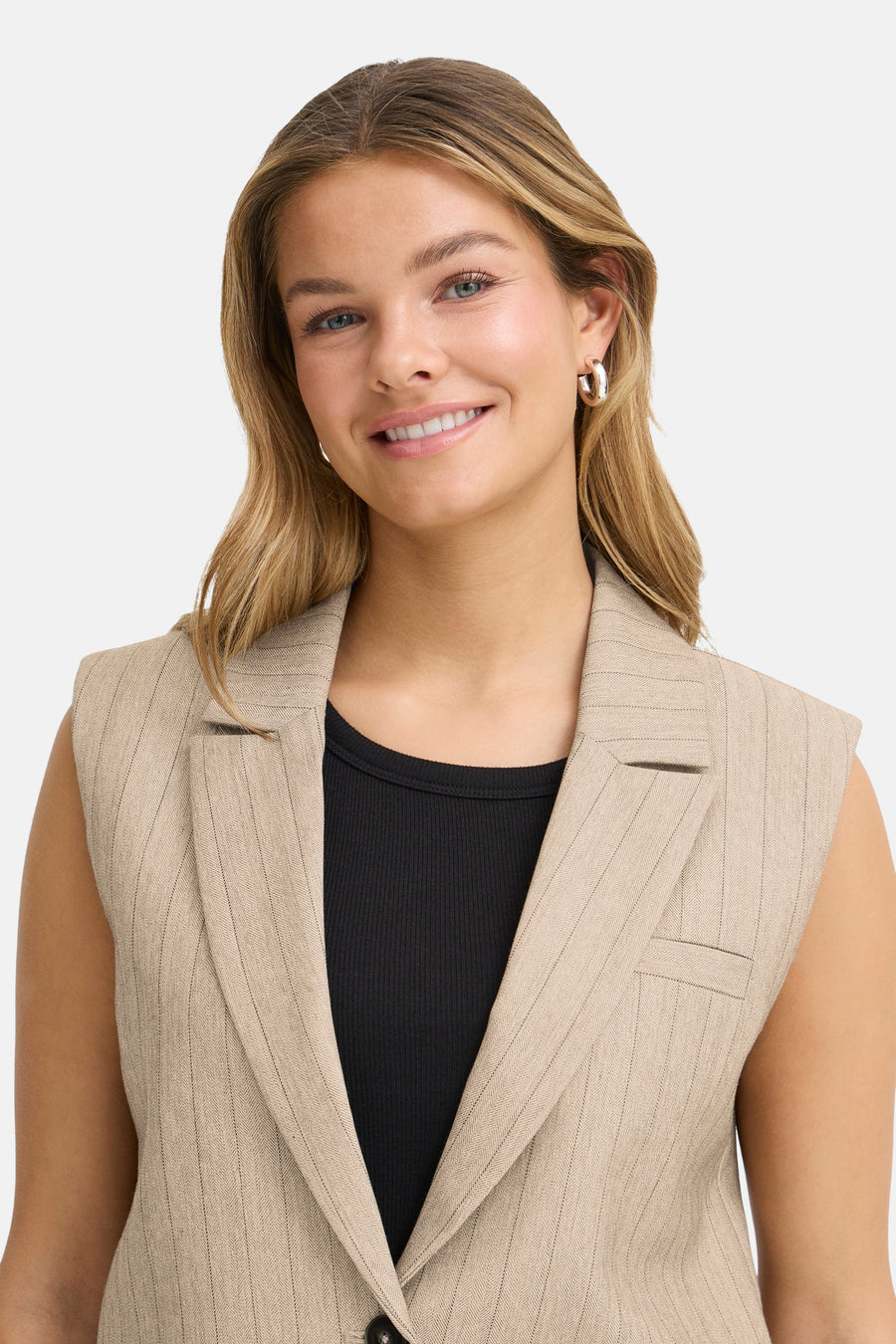 Beige mouwloos colbert van Fransa, met subtiel streepmotief, gedragen over een effen zwart T-shirt.