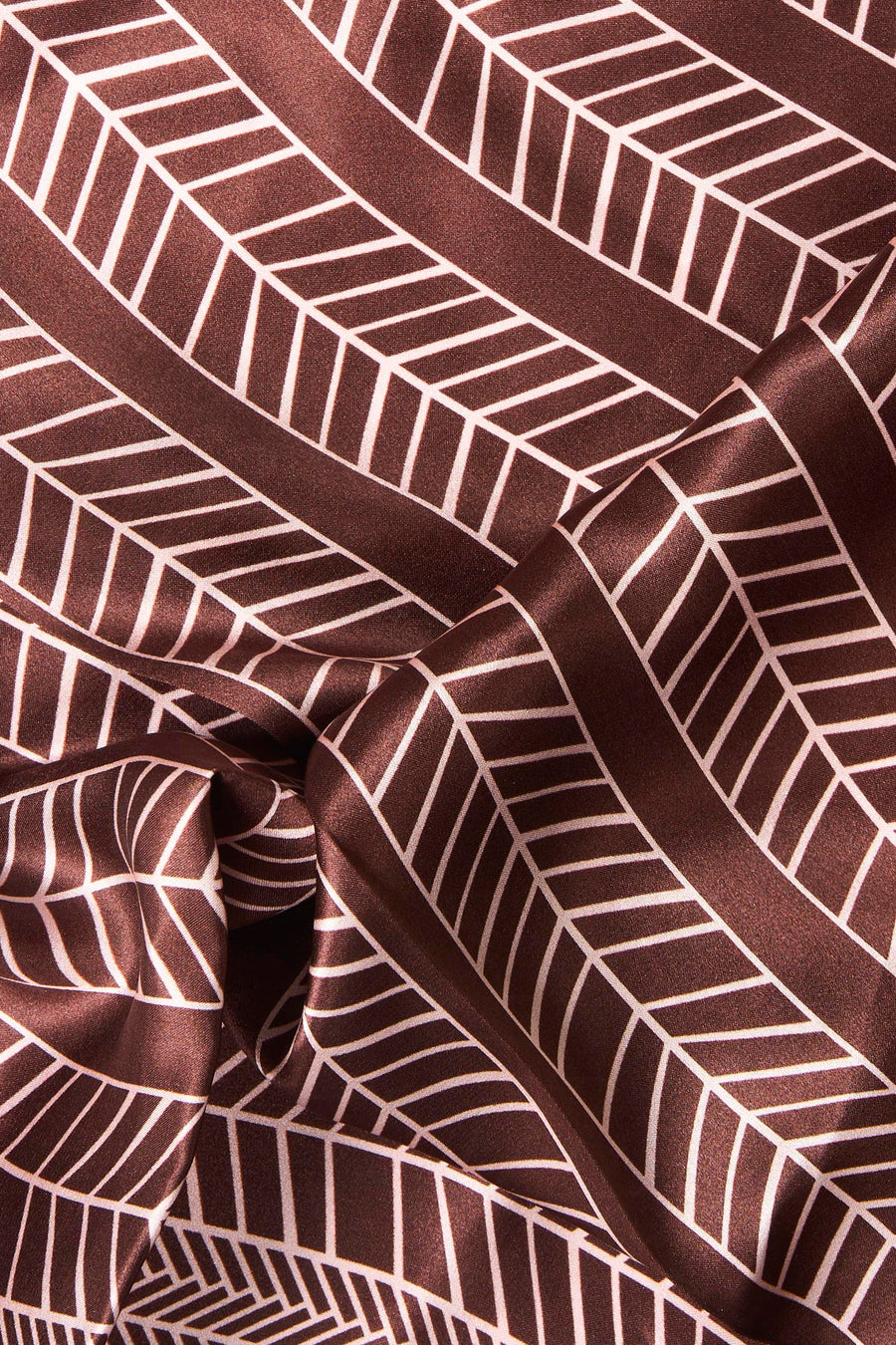 Multicolored foulard with geometric cube pattern in brown and white, featuring a silky texture and elegant folds.