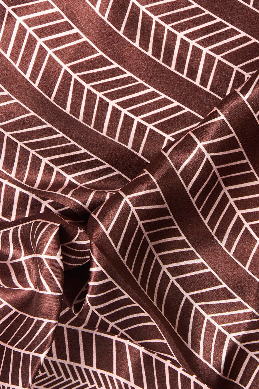 Multicolored geometric patterned foulard in rich brown with white lines, soft satin texture, close-up view
