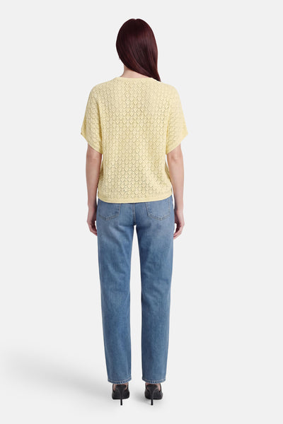 Pull jaune à manches courtes en maille ajourée de Fransa, motif losanges, porté de dos avec un jean bleu.