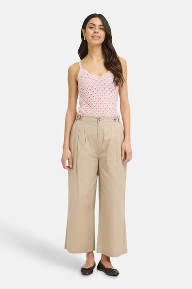 Pantalon beige de Fransa, coupe large plissée avec boutons, porté avec un débardeur rose.