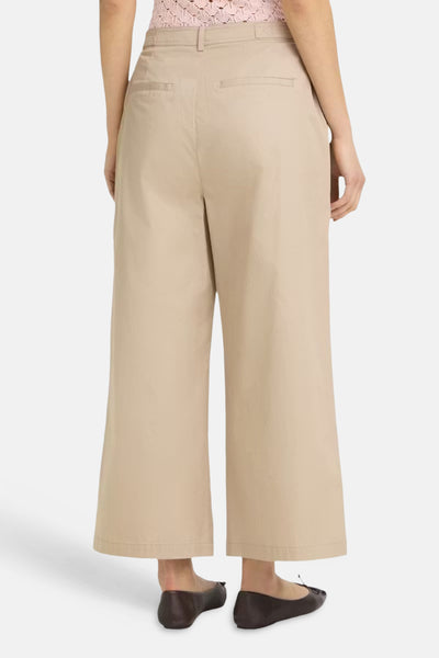 Pantalon large beige de Fransa® à taille haute et longueur cropped, avec poches arrières, porté de dos avec un top rose et des ballerines.