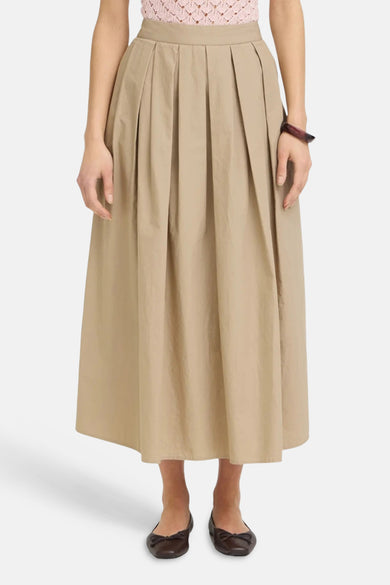 Lange beige rok van Fransa met elastische taille, van achteren gezien, gedragen met een roze top en bruine ballerina's.