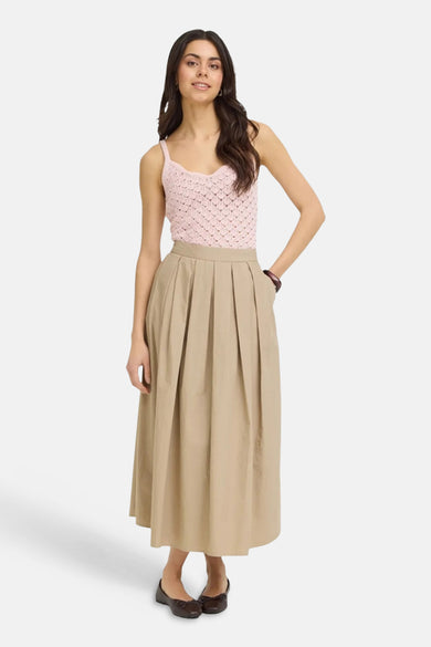 Jupe longue plissée beige de Fransa avec poches, portée avec un haut en crochet rose.