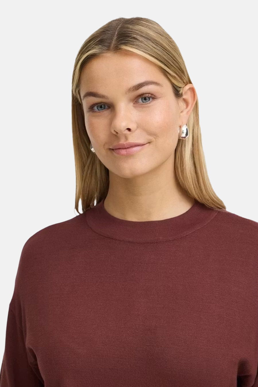Burgundy crewneck sweater by Fransa® with ribbed neckline, soft knit texture, front view on model wearing silver hoop earrings