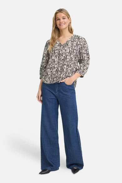 Multicolored short-sleeve blouse with floral print and V-neck, worn with blue wide-leg jeans and black pointed-toe shoes, front view.