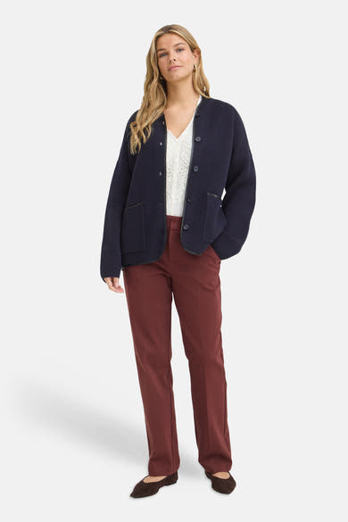 Gilet bleu marine à boutons de Fransa®, en maille épaisse avec poches et bordure contrastante, porté sur un haut blanc ajouré et pantalon bordeaux.