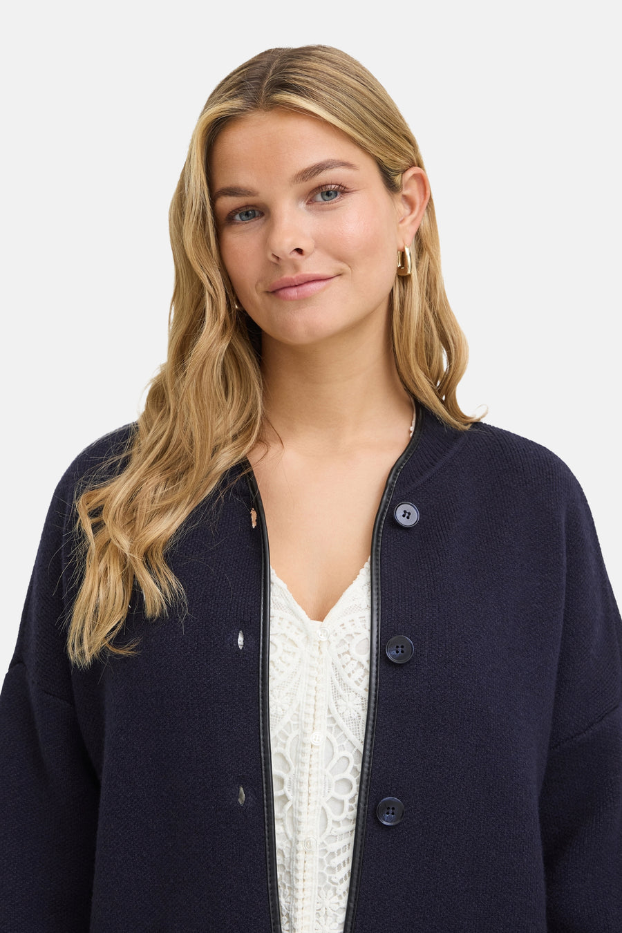 Gilet bleu en tricot épais par Fransa®, boutonné avec bordure contrastante, porté sur chemise blanche dentelle, vue de face.