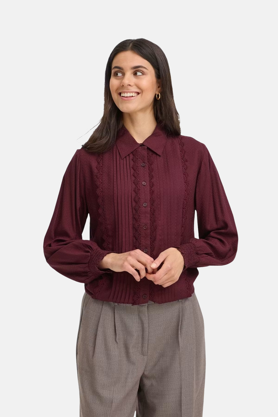Bordeaux long-sleeve blouse with pleated front and lace trim, worn by model with gray trousers, front view