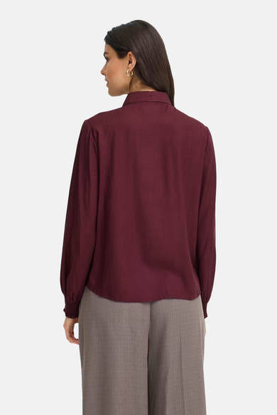 Bordeaux long-sleeve blouse with textured fabric, shown from back on model wearing gray trousers