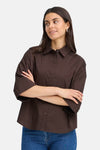 Brown long-sleeve shirt with button-down front and pointed collar, worn by model in lifestyle pose, paired with blue jeans