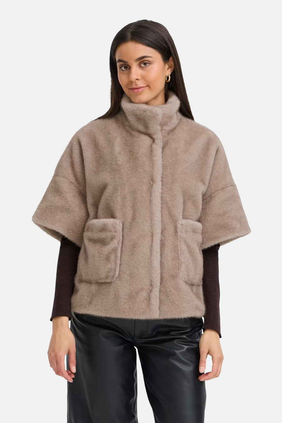 Beige fuzzy short coat with turtleneck and front pockets, worn over dark long-sleeve top and black shiny pants, front view