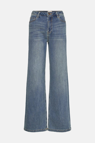 Wijde spijkerbroek in middieblauw denim van FREEQUENT, gedragen met een lamswollen vest en witte laarzen.