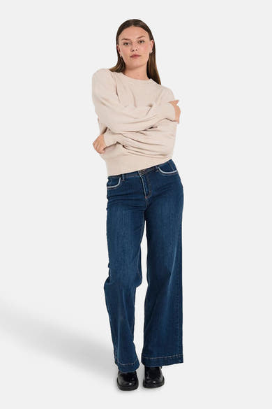 Beige ronde hals trui van FREEQUENT, gedragen met een donkerblauwe wijde pijpen jeans en zwarte schoenen.
