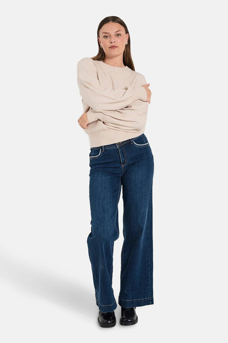 Beige ronde hals trui van FREEQUENT, gedragen met een donkerblauwe wijde pijpen jeans en zwarte schoenen.