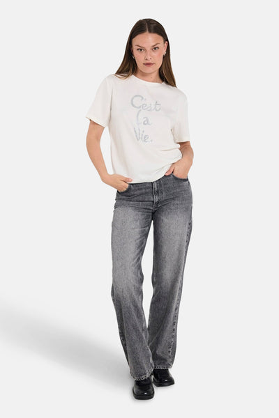 Jean droit en denim gris foncé de FREEQUENT, porté avec un t-shirt blanc à motif.
