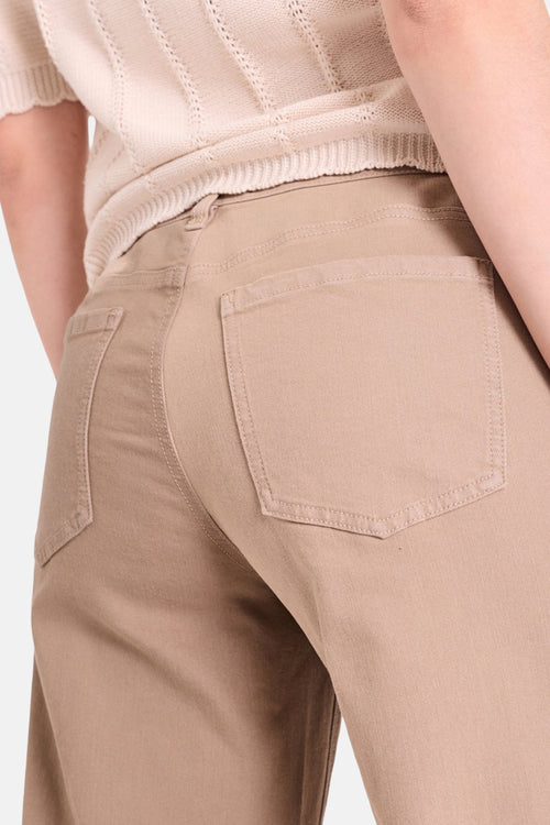 Jeans coloré beige de FREEQUENT, avec poches arrières, porté avec un pull en tricot.
