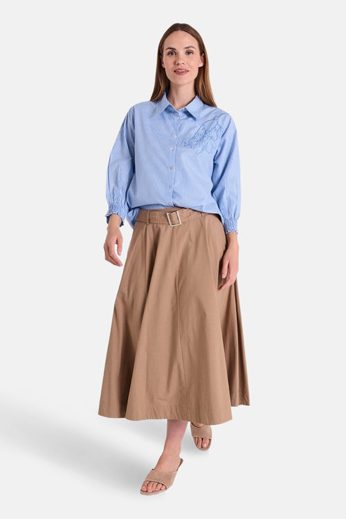Jupe 3/4 beige de FREEQUENT, coupe évasée, portée avec une chemise rayée bleu et des sandales neutres.