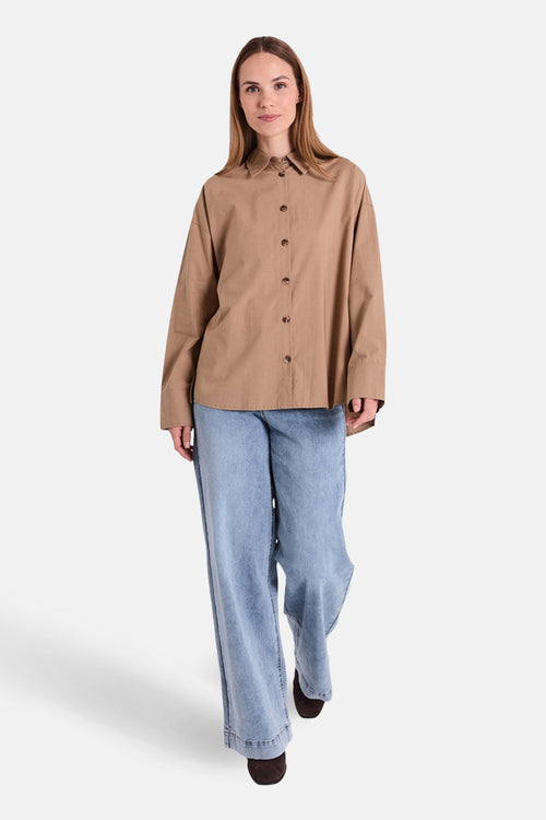 Chemisier à manches longues beige de FREEQUENT avec fermeture boutonnée et porté avec un jean ample.