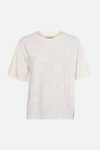 Wit T-shirt met korte mouwen van FREEQUENT, bloemenpatroon in reliëf, gedragen met een zwarte legging en lakleren pumps.