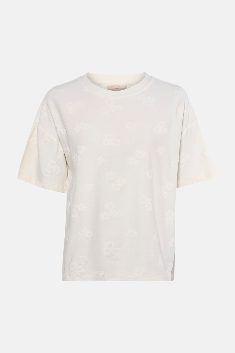 Wit T-shirt met korte mouwen van FREEQUENT, bloemenpatroon in reliëf, gedragen met een zwarte legging en lakleren pumps.