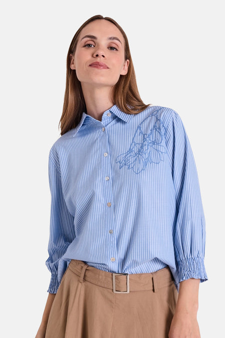 Chemisier bleu rayé à manches longues de FREEQUENT, avec motif floral brodé et ceinture marron portée à la taille.