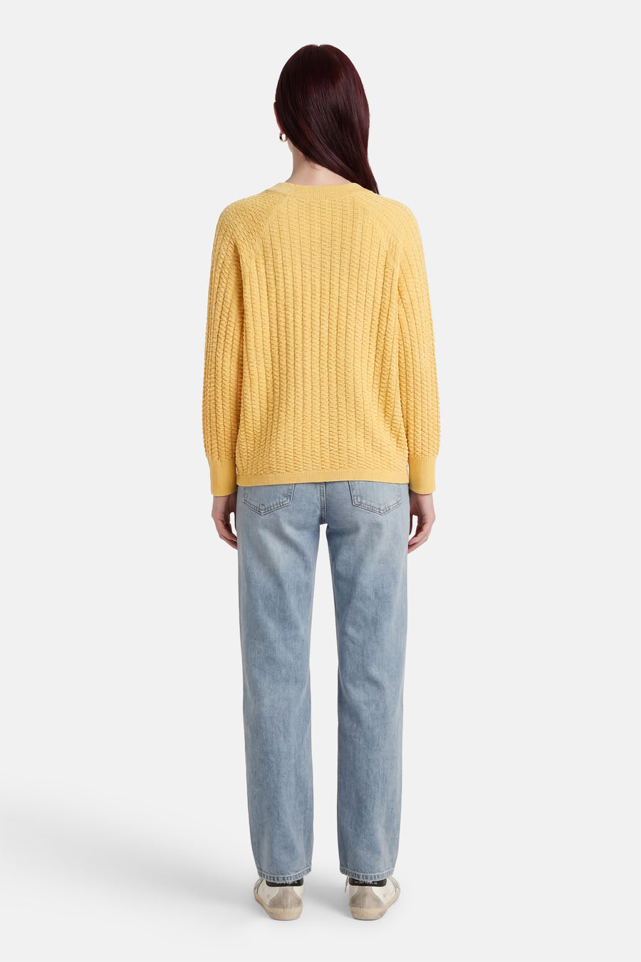 Pull jaune de FREEQUENT, en maille texturée, porté avec un jean bleu et des baskets blanches, vue de dos.